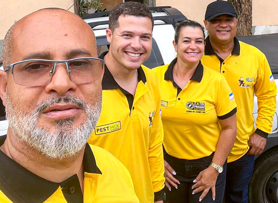 Equipe da Extin Pragas uniformizada ao lado do veículo de atendimento