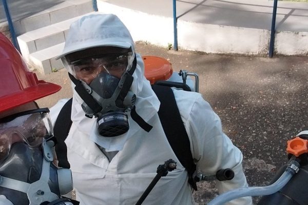 Técnico da Extin Pragas com macacão, respirador e pulverizador costal antes da aplicação